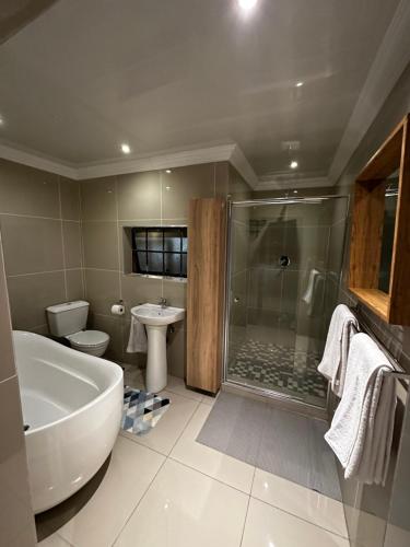 a bathroom with a tub and a shower and a sink at Silverton Private Apartment in Pretoria