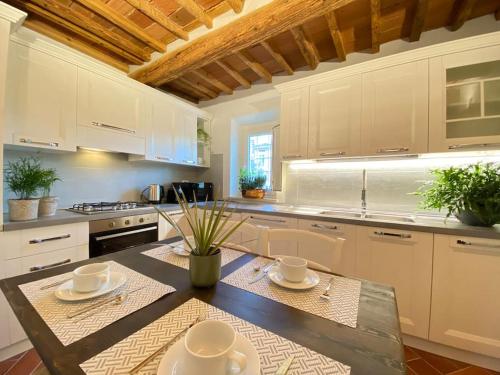 una cocina con armarios blancos y una mesa con platos. en Viaggiare Smart [Wi-fi, TV HD, Spazio di lavoro, Parcheggio gratuito nella struttura,], en Capannori