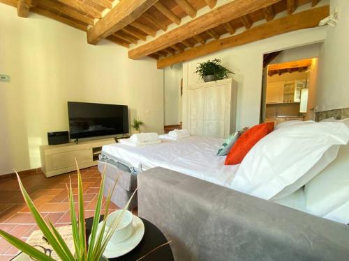 una camera con letto bianco e TV a schermo piatto di Viaggiare Smart [Wi-fi, TV HD, Spazio di lavoro, Parcheggio gratuito nella struttura,] a Capannori