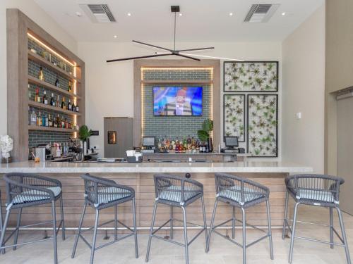 a bar with four stools in a room at Hyde Beach House - 2BD-2BA MANSION WITH DIRECT OCEAN VIEW, Resort Amenities, Rooftop Pool and Hot tub, Tennis court, few min walk to the ocean in Hollywood