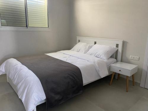 ein Schlafzimmer mit einem großen Bett mit weißer Bettwäsche und einem Fenster in der Unterkunft דירת נופש התבור Hatvor condo in Shadmot Devora
