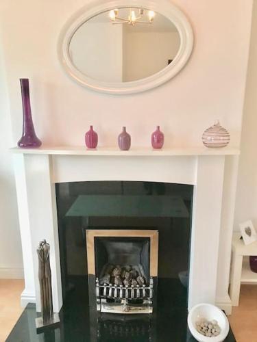 a mirror above a fireplace with purple vases at Willow in Foleshill