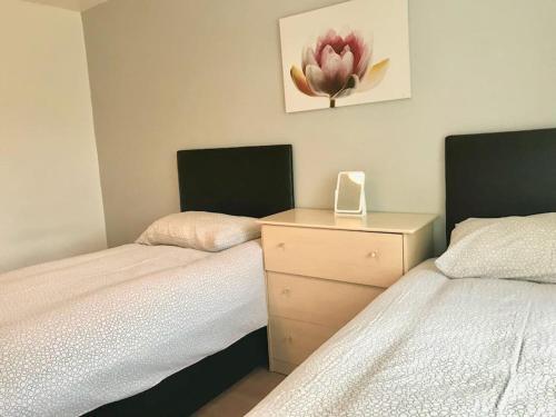a bedroom with two beds and a dresser with a flower on the wall at Willow in Foleshill