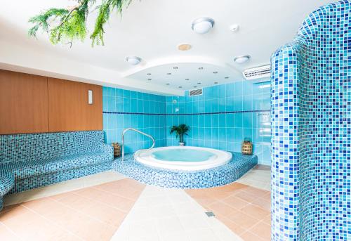 a blue tiled bathroom with a tub in a room at Hotel Petrovy kameny in Karlova Studánka