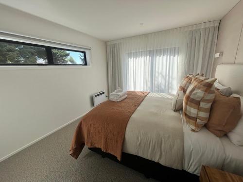 特卡波湖的住宿－Tekapo Toi Toi，一间卧室设有一张大床和一个窗户。