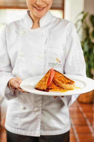 a woman holding a plate with a sandwich on it at Uzhupud Garden Hotel & Lodge in Paute