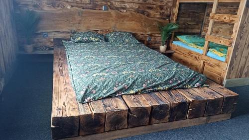 a wooden bed with a green comforter in a room at Planinski dom Janče in Ljubljana