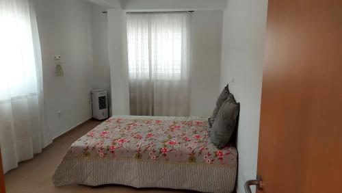 a bedroom with a bed with a flowered blanket and a window at Apartamento F3, Lazareto - Mindelo in Mindelo