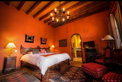 1 dormitorio con paredes de color naranja, 1 cama y lámpara de araña en Casa Don Pascual Hotel Boutique Sweet Home en San Miguel de Allende