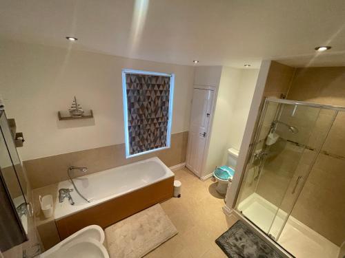 a bathroom with a bath tub and a shower at Beanies LorneStreet Four Bed House in Swindon
