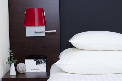 a red lamp on a bed with a white pillow at Best Western Plus Plaza Hotel Graz in Graz