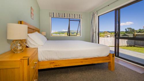 1 dormitorio con cama y ventana grande en Ravishing Redwings, en Whitianga