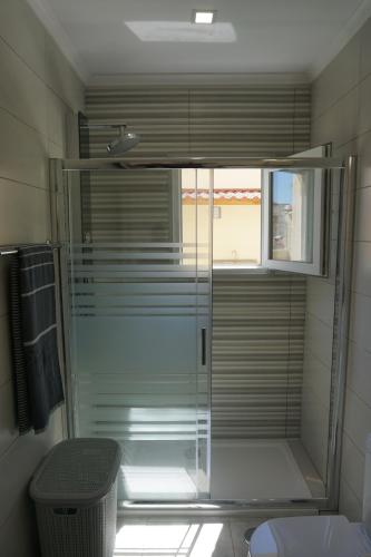 y baño con ducha de cristal y ventana. en Sunny Home, en Amadora