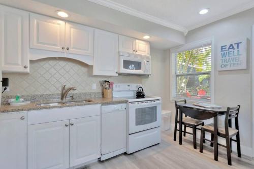 a kitchen with white cabinets and a sink and a table at Sea Gem One bed one bath charmer steps to beach in Bradenton Beach