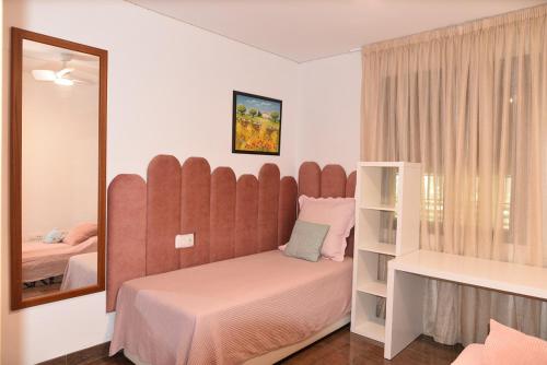 1 dormitorio con 1 cama con cabecero grande y espejo en Buena vista, en Fuengirola