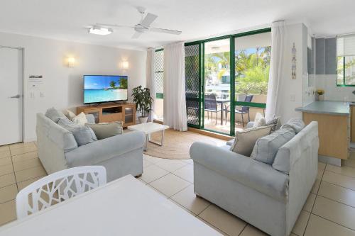 a living room with two couches and a tv at Headland Gardens Holiday Apartments in Alexandra Headland