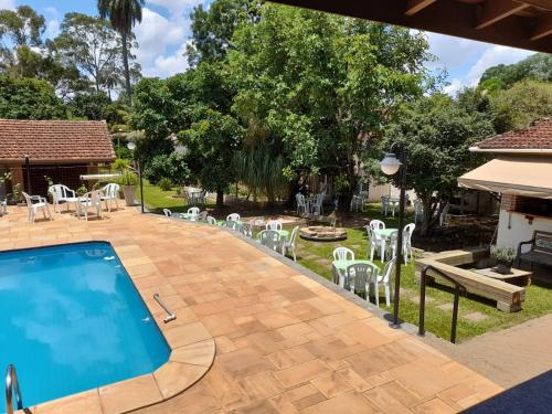 a patio with a swimming pool and white chairs at Chácara PALOMA in Jaguariúna