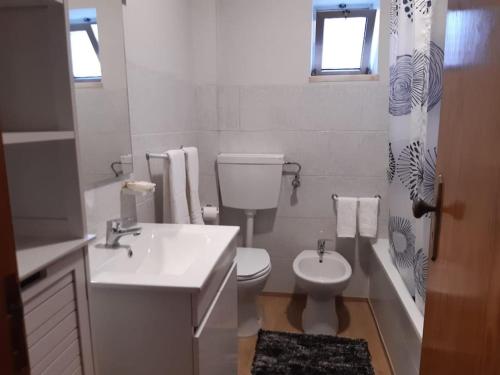 La salle de bains blanche est pourvue de toilettes et d'un lavabo. dans l'établissement Moradia Félix - Apartamento Félix, à Manteigas