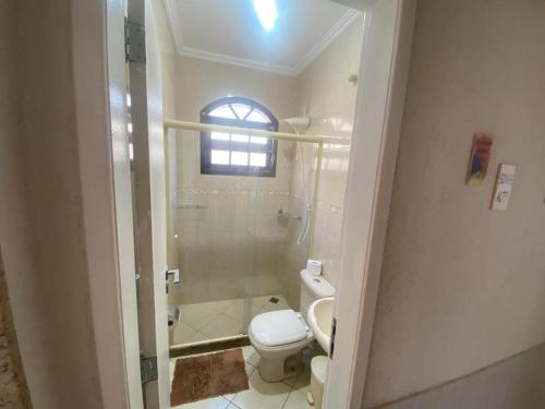 a bathroom with a toilet and a shower with a window at Casa Três Amores in Búzios