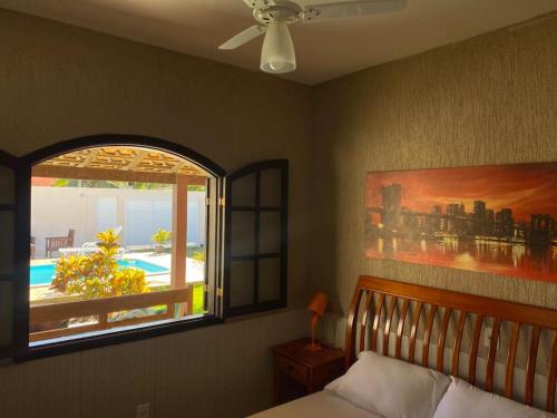 a bedroom with a bed and a window with a view at Casa Três Amores in Búzios