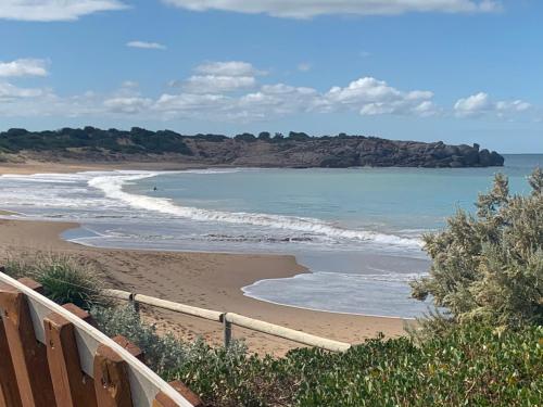 a beach with a wooden fence and the ocean at The Beach House in Middleton
