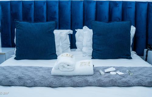 ein Bett mit blauen Kissen und einem Handtuch darauf in der Unterkunft Henry George Guest House in Pretoria