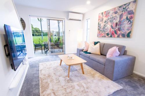 a living room with a couch and a table at 2 Bedrooms overlooking Park - Exquisite Views in Christchurch