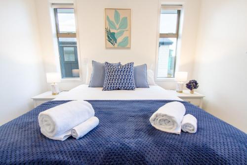 a bedroom with a blue bed with towels on it at 2 Bedrooms overlooking Park - Exquisite Views in Christchurch