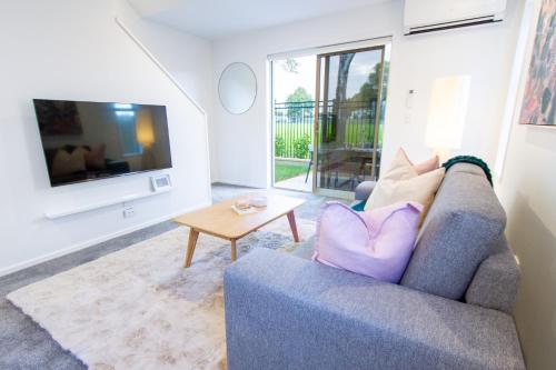 a living room with a couch and a tv at 2 Bedrooms overlooking Park - Exquisite Views in Christchurch
