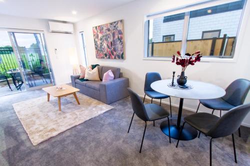 a living room with a table and chairs and a couch at 2 Bedrooms overlooking Park - Exquisite Views in Christchurch