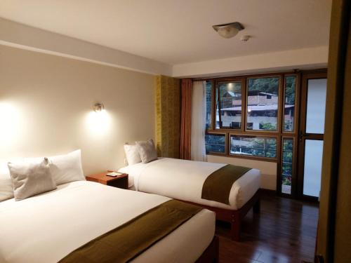 a hotel room with two beds and a window at Hotel Pucara Machupicchu in Machu Picchu