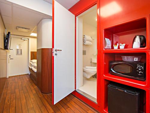 a red bathroom with a toilet and a microwave at Omena Hotel Helsinki Lönnrotinkatu in Helsinki