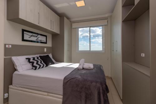 Habitación pequeña con cama y ventana en Pôr do sol 18º andar vista da cidade CENTRAL, Garagem NOVO en Passo Fundo