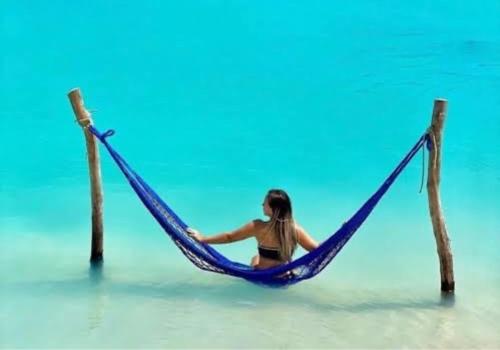 a woman sitting in a hammock in the water at casa jasmin in Jericoacoara