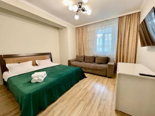 um quarto com uma cama verde e um sofá em Жк «Abay 130» комфорт и уют em Almaty