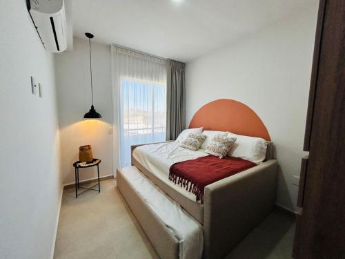 a small bedroom with a bed with an orange headboard at alberca tipo playa,10 min de la playa by G P S rentas in Mazatlán