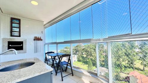 ein Badezimmer mit großem Fenster mit Tisch und Stühlen in der Unterkunft Viva em um Resort Paradisíaco na Brava 100m do Mar in Itajaí