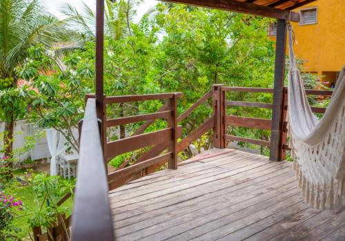 a hammock on a wooden porch with trees at casa jasmin in Jericoacoara