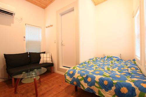 a bedroom with a bed and a couch and a glass table at Yuuwa Guesthouse in Mifune
