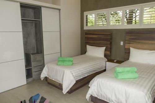 - une chambre avec 2 lits et des serviettes vertes dans l'établissement Casa Kaiman - Villa Azul, à Nosara