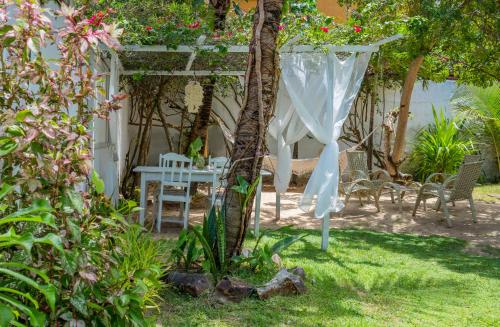 a garden with a white pergola and a table and chairs at casa jasmin in Jericoacoara