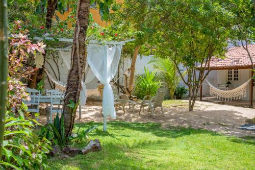 a garden with chairs and a white canopy and a table at casa jasmin in Jericoacoara