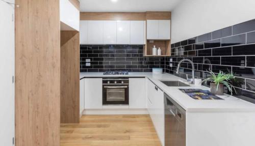 una cocina con encimeras blancas y azulejos negros en Private room near Auckland Airport, en Auckland