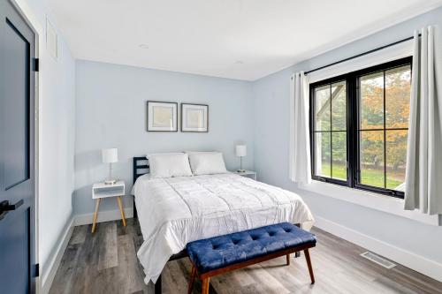 een witte slaapkamer met een bed en een raam bij Marble & Sun in Hampton Bays