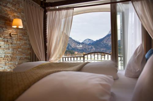 a bedroom with a large window with a mountain view at Hotel Das Rübezahl in Schwangau