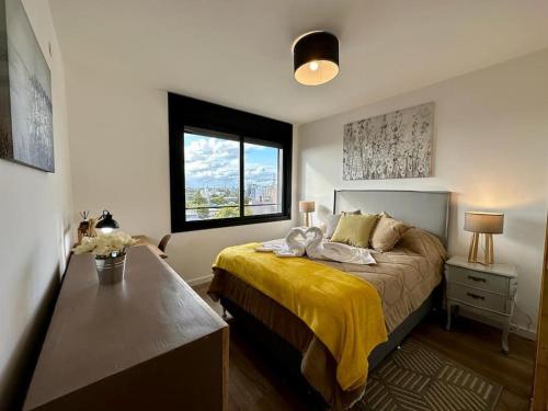 a bedroom with a bed with a yellow blanket and a window at Brand New apartment near port - piso 11 in Montevideo