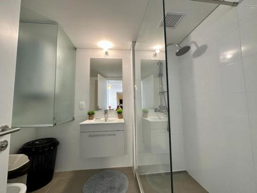 a white bathroom with a shower and a sink at Brand New apartment near port - piso 11 in Montevideo