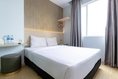 Habitación de hotel con cama blanca y ventana en Swasana Hotel near Plaza Medan Fair Mitra RedDoorz, en Medan