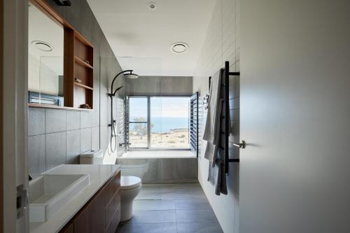 a bathroom with a sink and a toilet and a window at Luxury Ocean View house Saltbush Farm in Cape Jervis