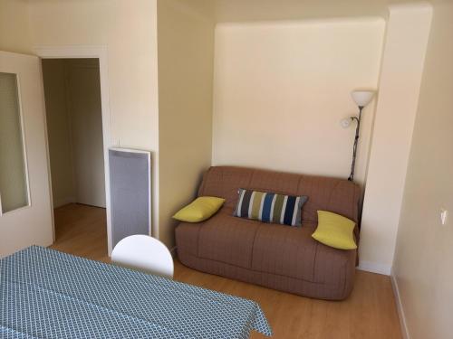 - un salon avec un canapé brun et des oreillers jaunes dans l'établissement Studio rénové près de la plage et forêt à Notre-Dame-de-Monts - 2 pers - Balcon et WIFI - FR-1-540-134, à Notre-Dame-de-Monts